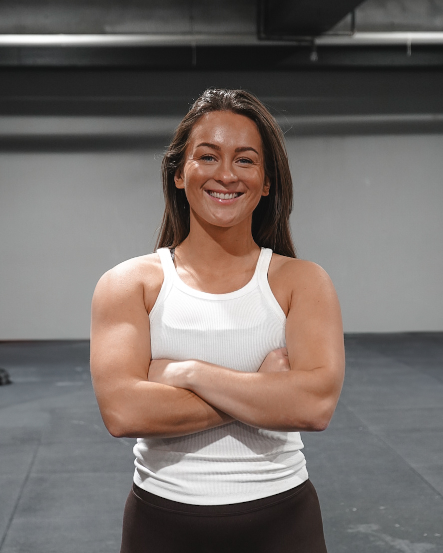 Smilende kvinne med kryssete armer etter trening